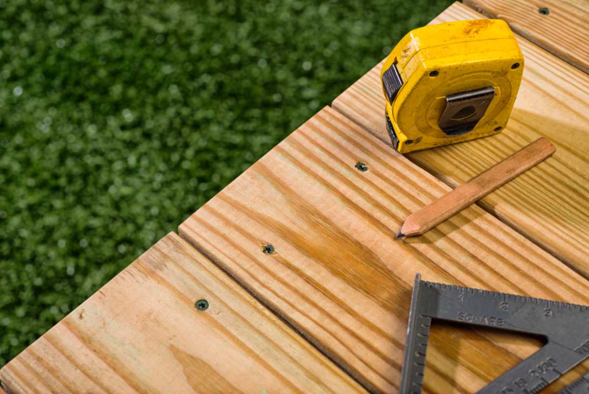 Carpenter's Pencil, square and tape sitting on a wood deck